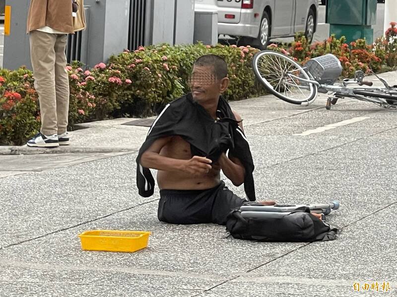 打赤膊趴地乞讨的男子,熬不住水泥地高温爬起身穿衣。(记者黄良杰摄) 打赤膊趴地乞讨的男子,熬不住水泥地高温爬起身穿衣。(记者黄良杰摄)