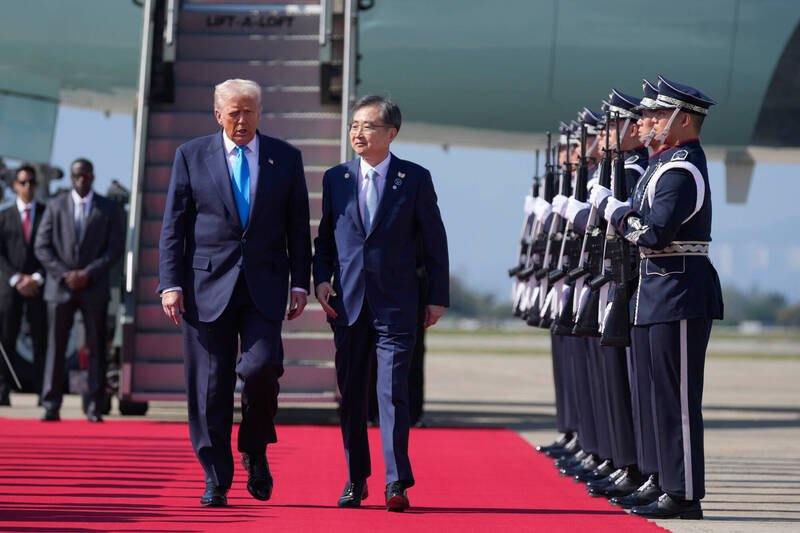 美国总统川普（左）29日飞抵南韩釜山金海国际机场，展开其亚洲行的最后一站，南韩方面派出官员与仪队迎接。（美联社）