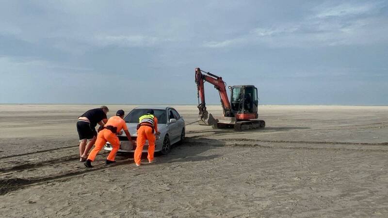 温寮安检所协调当地业者出动挖土机以拖带方式，协助民众的车辆脱困。（海巡署提供）