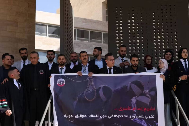 以色列国会初审通过针对「恐怖份子」的死刑法案，引发巴勒斯坦方面强烈反弹。图为巴勒斯坦律师9日在约旦河西岸城市希布伦，高举布条抗议此一立法。（法新社）