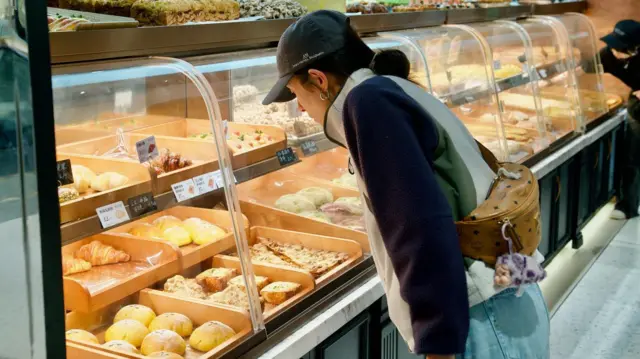 一位年轻女子正在检查展示柜里的面包。