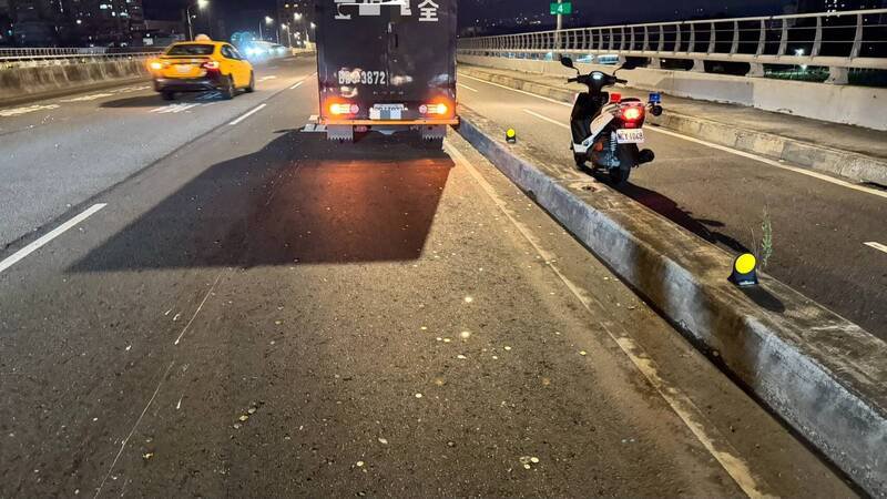 新北市一辆运钞车在板桥浮洲桥上掉落一袋零钱，保全员冒险摸黑捡拾。（记者吴仁捷翻摄）