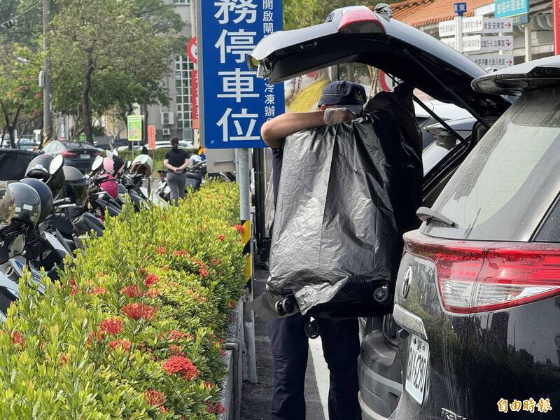 鉴识人员提著在陈男车上发现的行李箱至殡仪馆。（记者许丽娟摄）