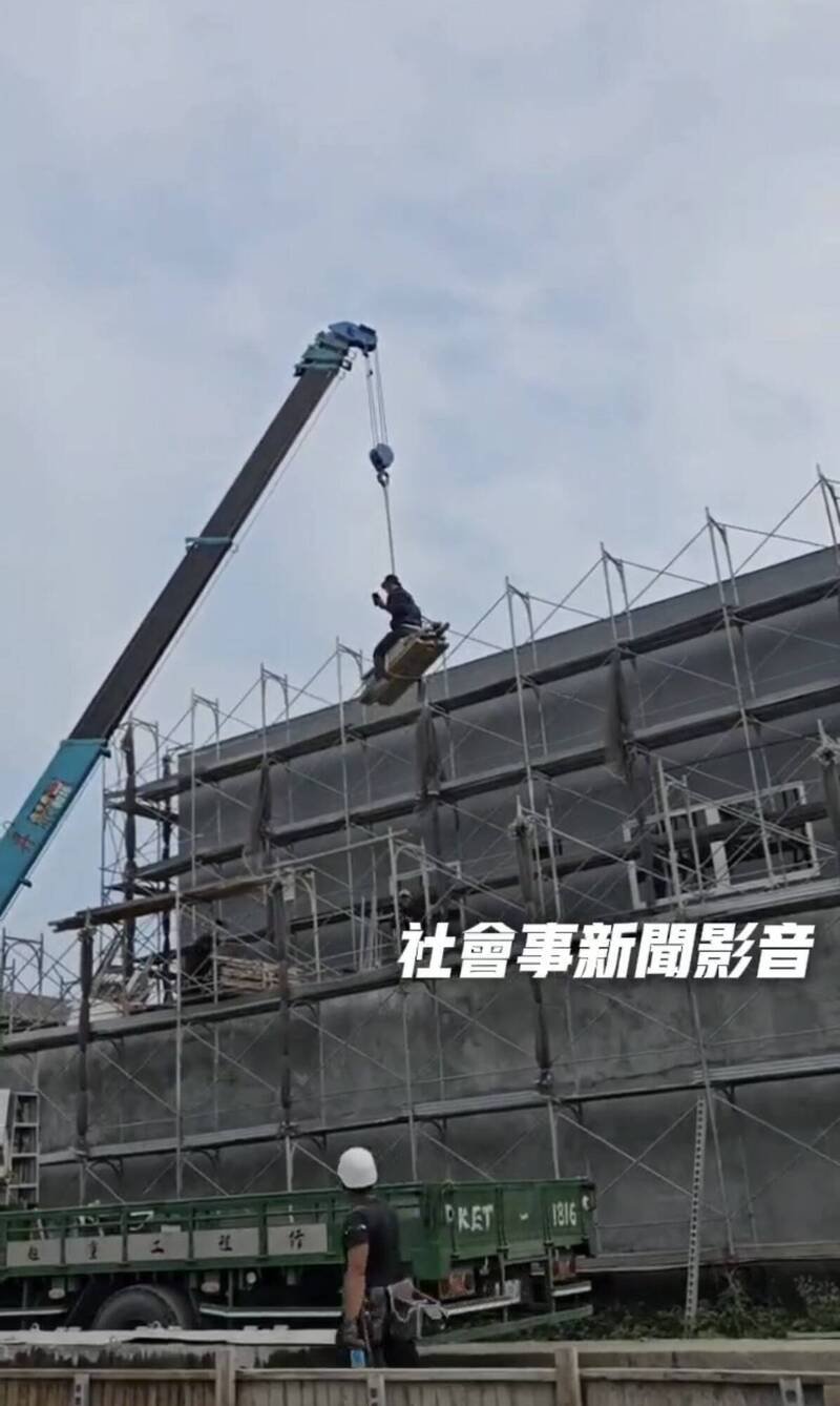 工人坐在模板上，随吊车从约4层楼高处垂降到地面。（取自「社会事新闻影音」）