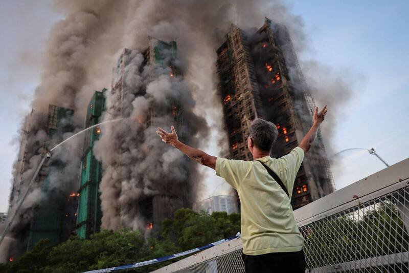 11月26日，宏福苑居民黄先生对著陷入火海的自家公寓大楼高举双臂。（路透）