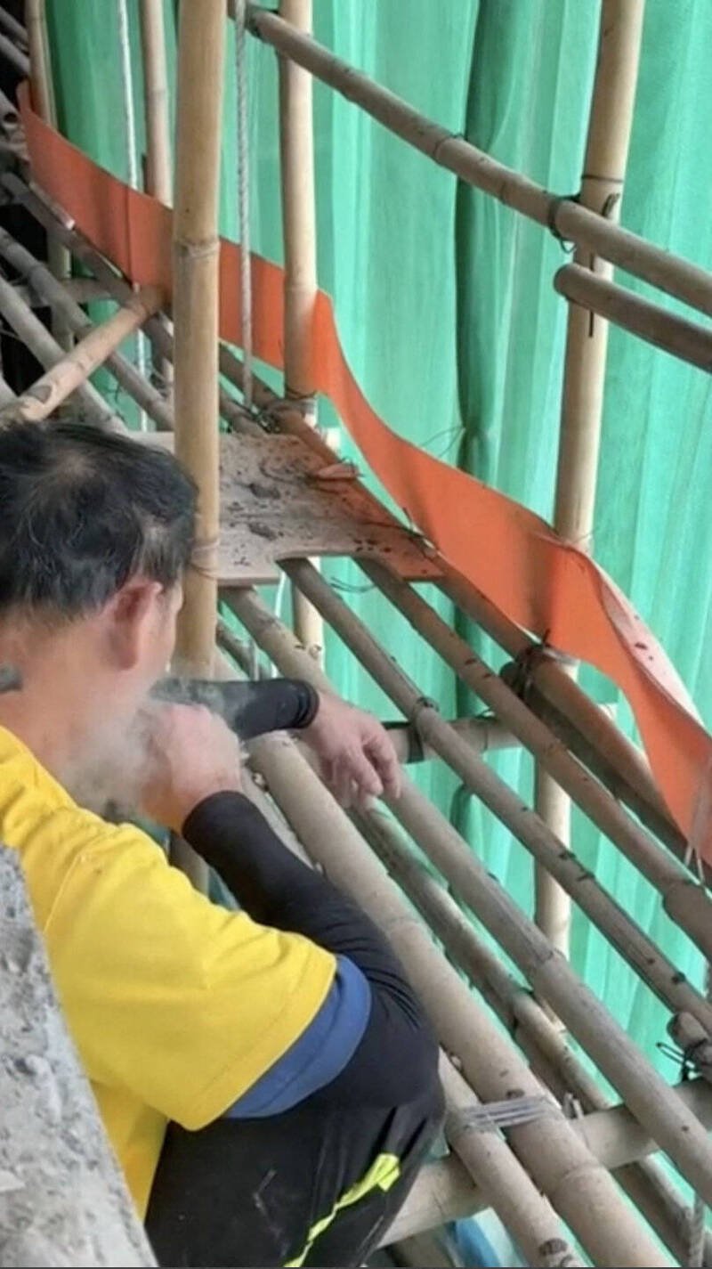 社群媒体流传1段拍摄日期不详的影片，显示日前发生大火的宏福苑社区外墙翻修工人，在竹制鹰架与绿色防护网旁吸烟。（路透）