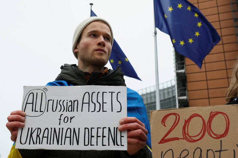 支持者17日在欧盟执委会外举标语，呼吁动用俄国资产援助乌克兰。（路透）