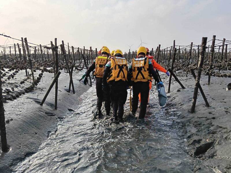蚵农海上作业惊见男尸挂蚵架，消防人员将遗体搬到陆地。（图由消防局提供）