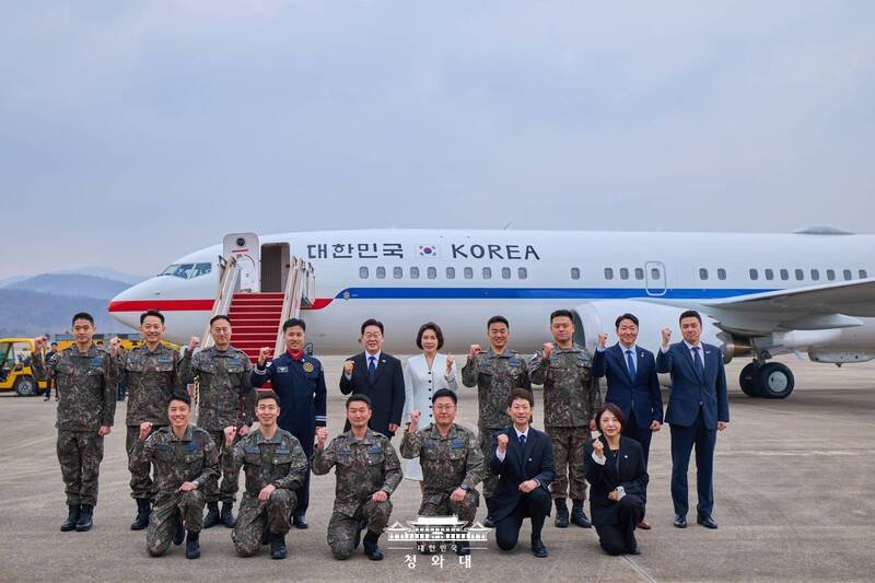 李在明（后排左5）15日登机前与工作人员在「空军二号」前合影留念。（图撷自X）